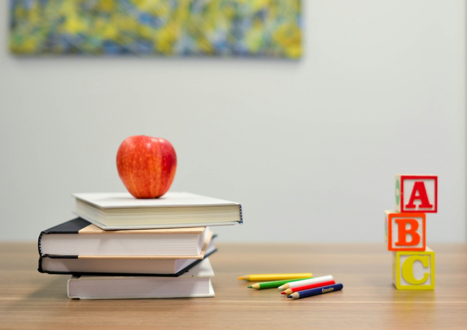 Books, an apple, pencils and alphabet blocks on a classroom table